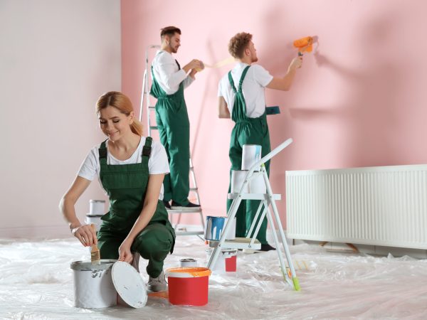 Team of professional decorators painting wall indoors. Home repair service